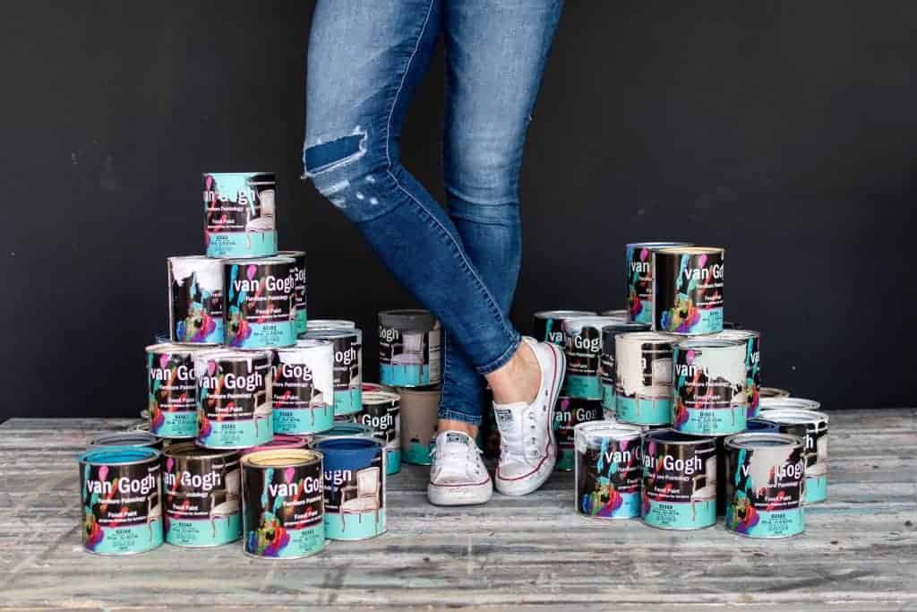 Collection of van Gogh Fossil paint cans surrounding the feet of Melanie Curley CEO of Mango Paint